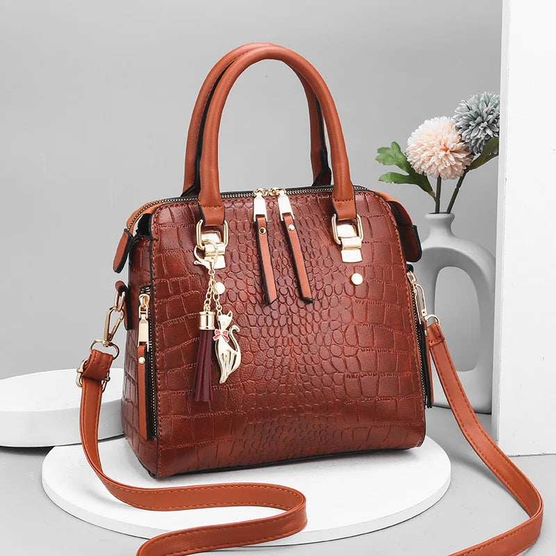Brown textured handbag with gold accents on a gray background