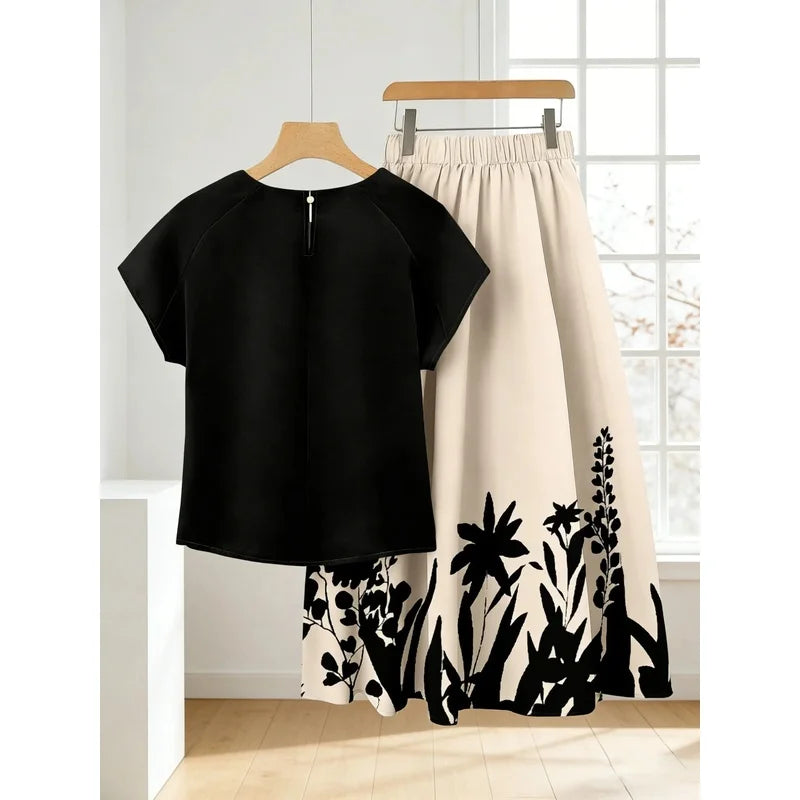 Back view of a black top with a cream botanical-print skirt; top has a small back zipper