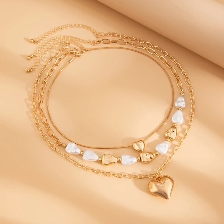 Gold heart-shaped beaded necklace on a beige background