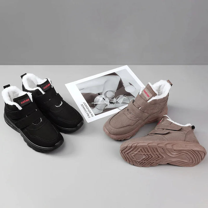 Pair of black and brown winter boots with white lining on a gray background.