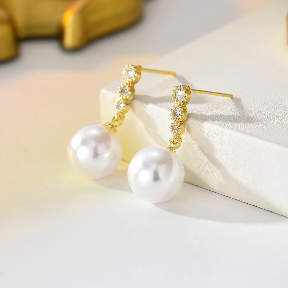 Gold-plated zircon band with large white pearl drops, dangle earrings on display
