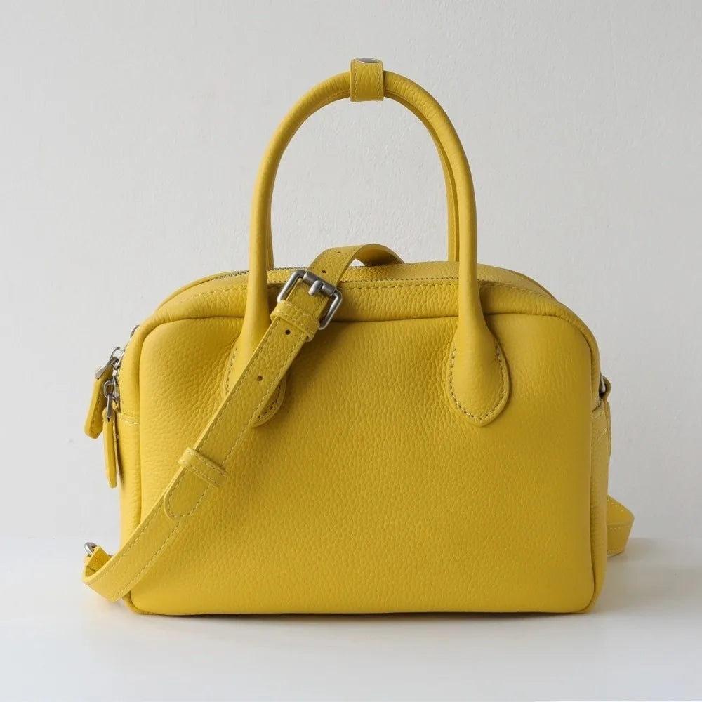 Yellow handbag with a strap on a light gray background
