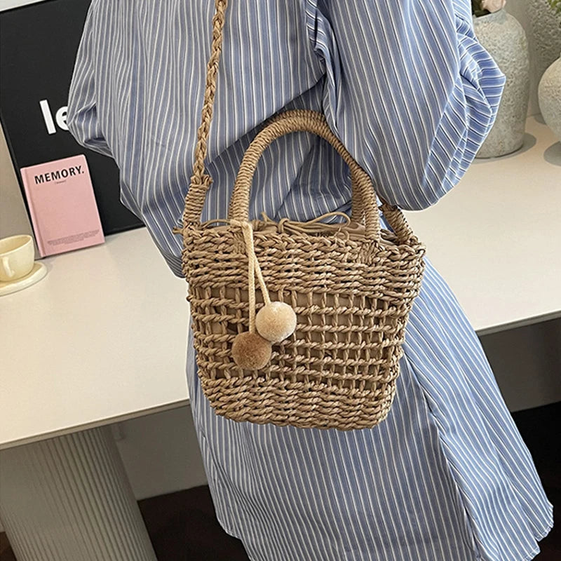 Two-tone knit straw bucket crossbody bag with pom-pom charm and braided top handles