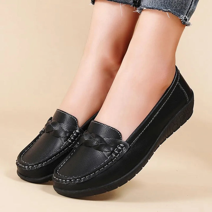Black loafers worn by a person on a beige background