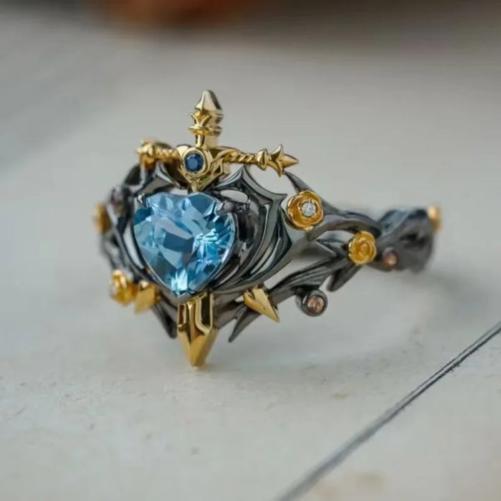 Heart blue zircon thorn ring with gold fleur tips, dark metal and adjustable opening