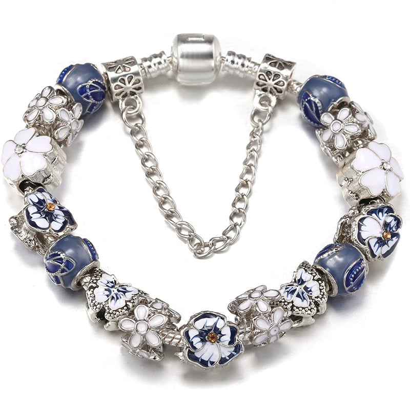 Silver charm bracelet with blue enamel beads and white flower and butterfly-shaped charms