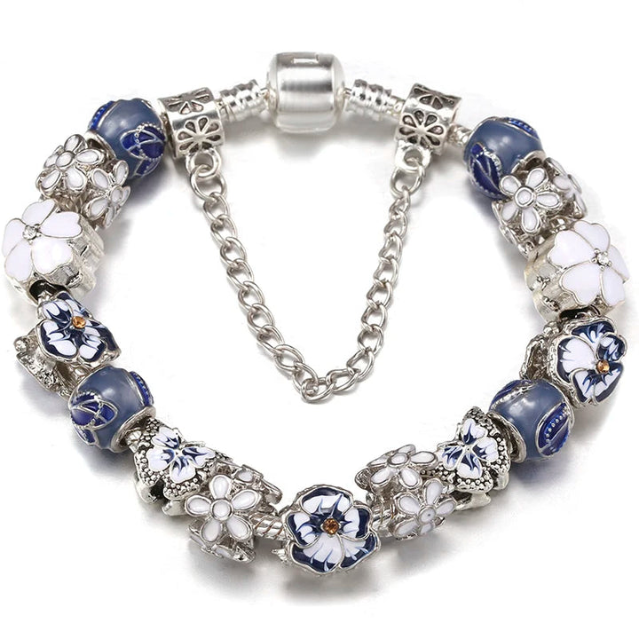 Silver charm bracelet with blue enamel beads and white flower and butterfly-shaped charms