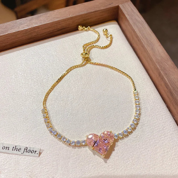 Gold-tone bracelet with pavé stones and pink heart-shaped center charm
