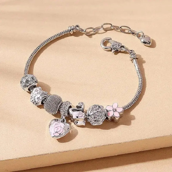 Silver-tone charm bracelet with rose pendant, flower charm, heart dangles, and mesh bead