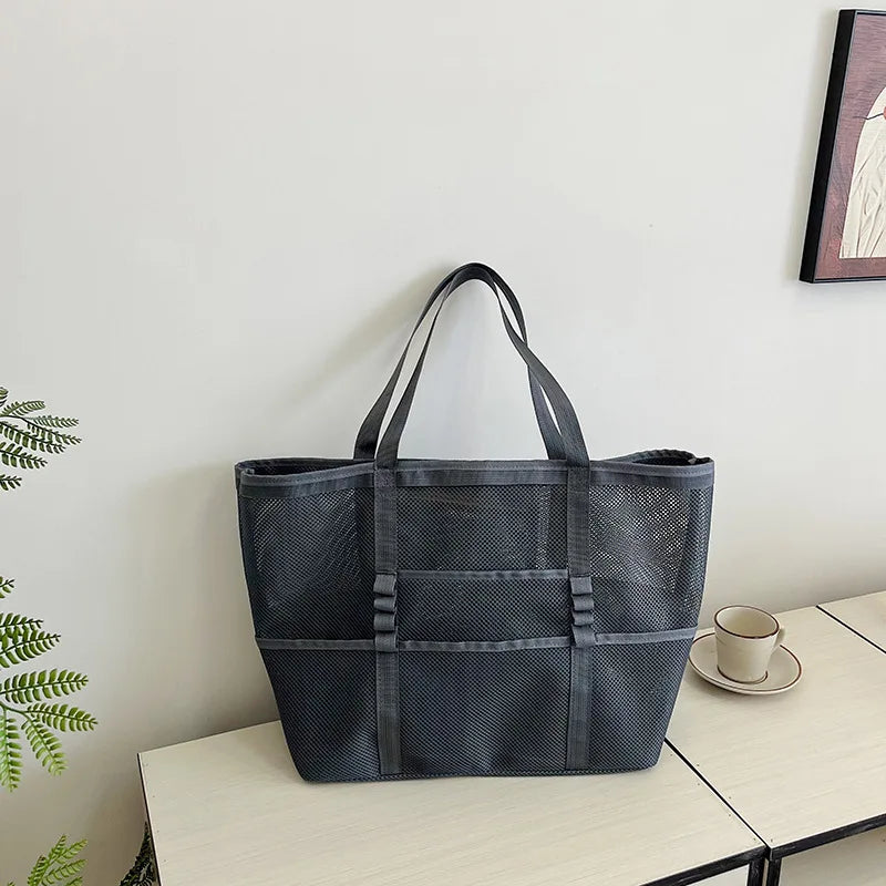 Dark gray sheer mesh tote bag with open top and wide straps, front organizer panels