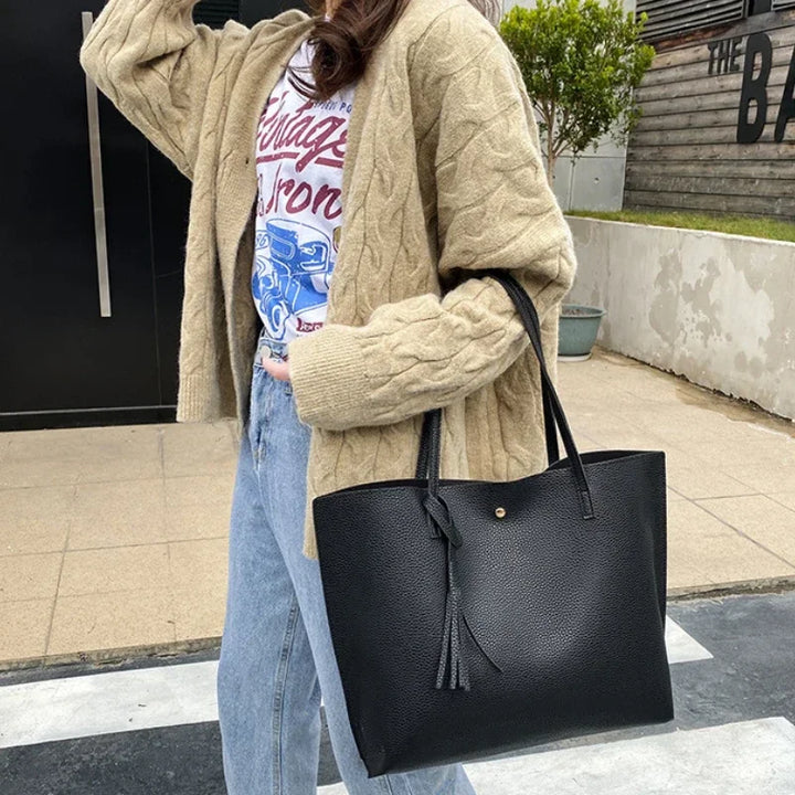 Person holding a black tote bag outdoors
