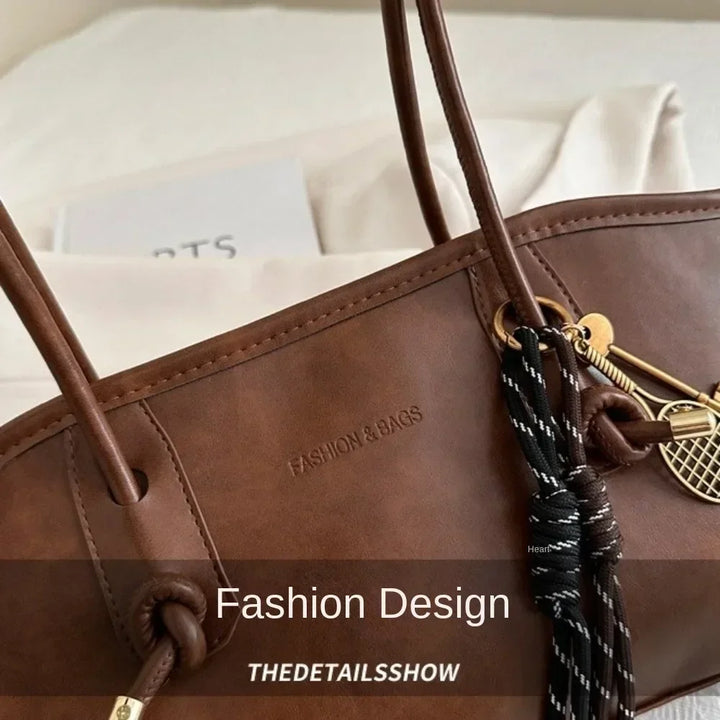 Brown PU leather tote handbag close-up with top strap rings and front design detail