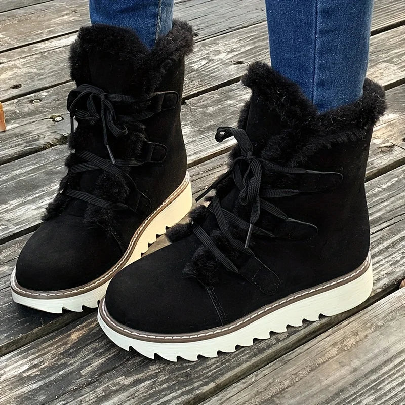 Black winter boots with fur trim on a wooden floor