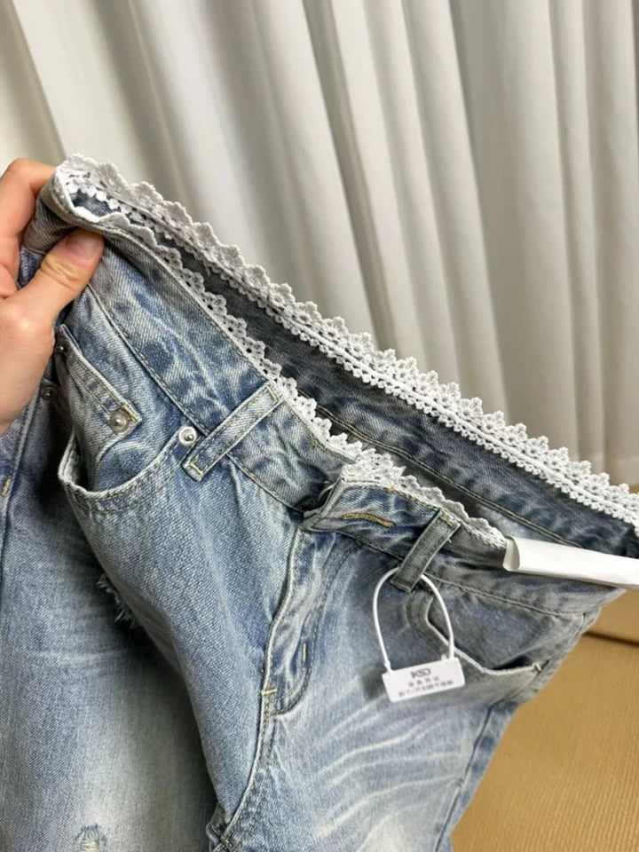 Close-up of light blue mid-rise jeans: lace-trim waistband, button fly, belt loops
