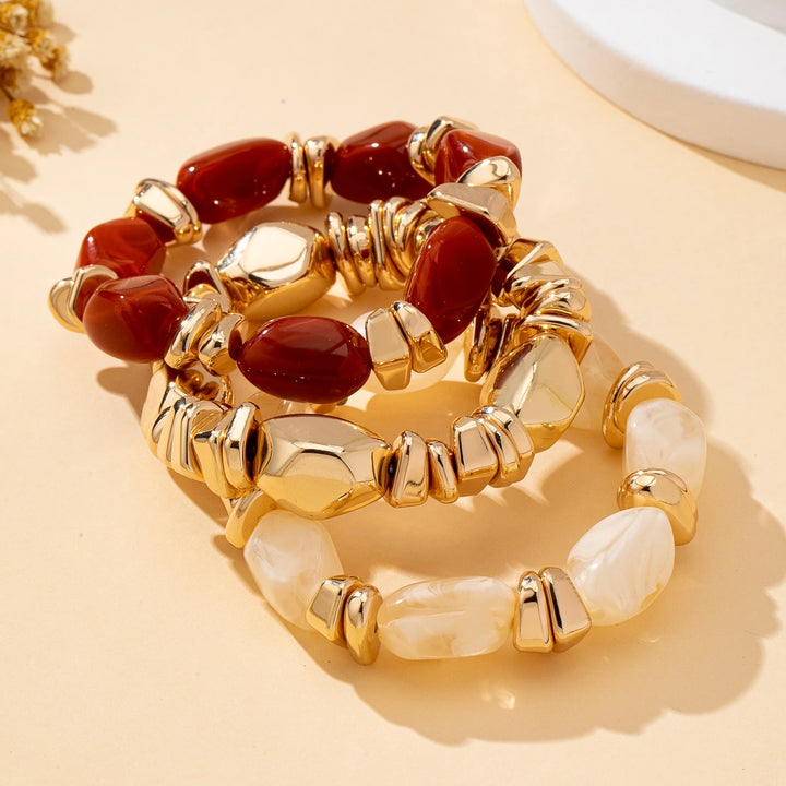 Stacked gold-tone acrylic bead bracelets with deep red and cream irregular beads
