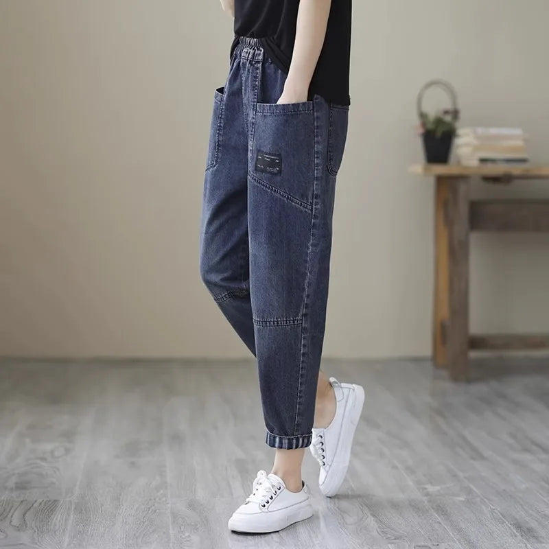 Person wearing blue jeans and white sneakers in a minimal indoor setting