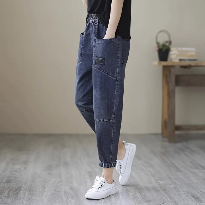 Person wearing blue jeans and white sneakers in a minimal indoor setting