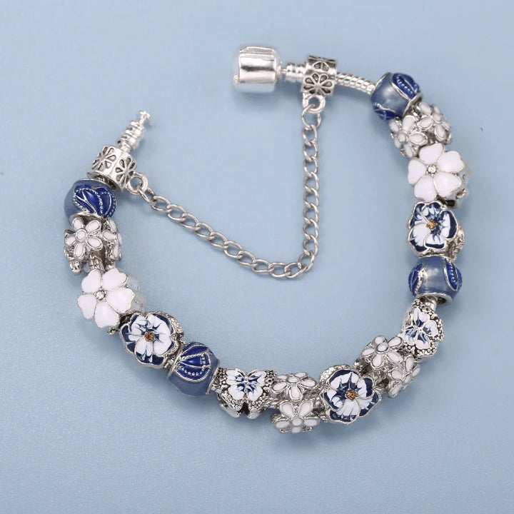 Silver charm bracelet with blue and white beads, flower spacers, and a small chain link