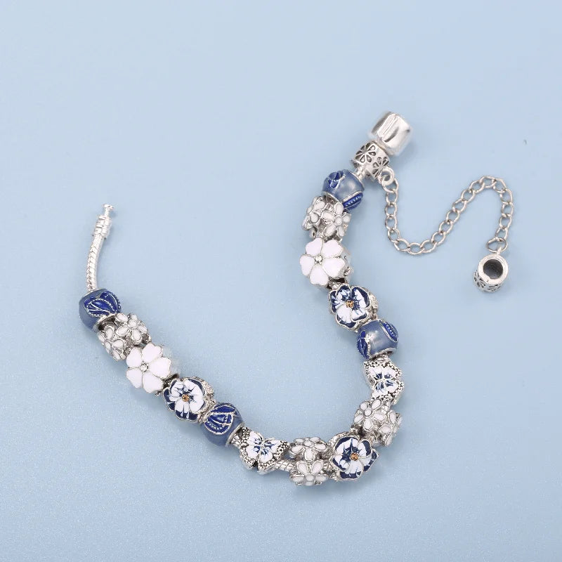 Silver charm bracelet with blue bead segments and white flower charms, shown laid out