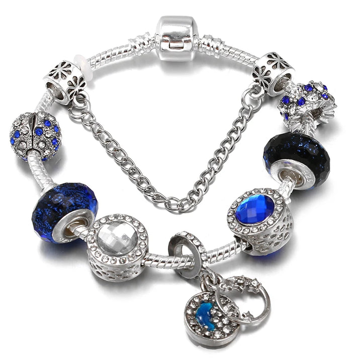 Silver charm bracelet with blue crystal beads, dark bead spacer, and oval heart pendant