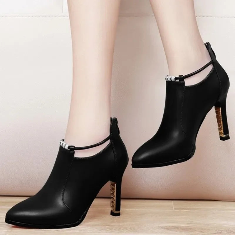 Black high-heeled shoes with ankle straps on a neutral background