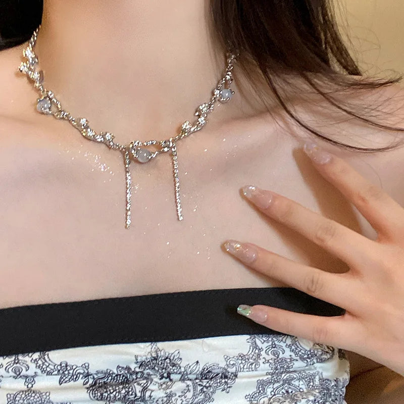 Close-up of a person wearing a sparkling necklace with a hand touching the chest.