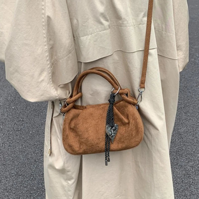 Tan suede mini crossbody hobo bag with short handles and long shoulder strap, drawstring top.