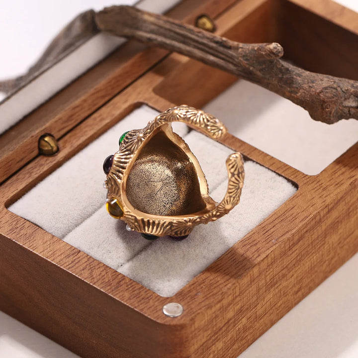 Open back of gold baroque ring with ornate leaf-like metal frame and colored stones