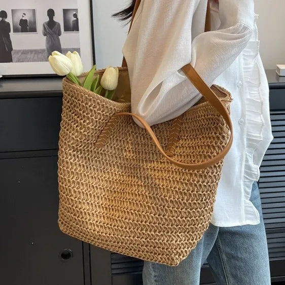 Person holding a woven bag with tulips against a neutral background
