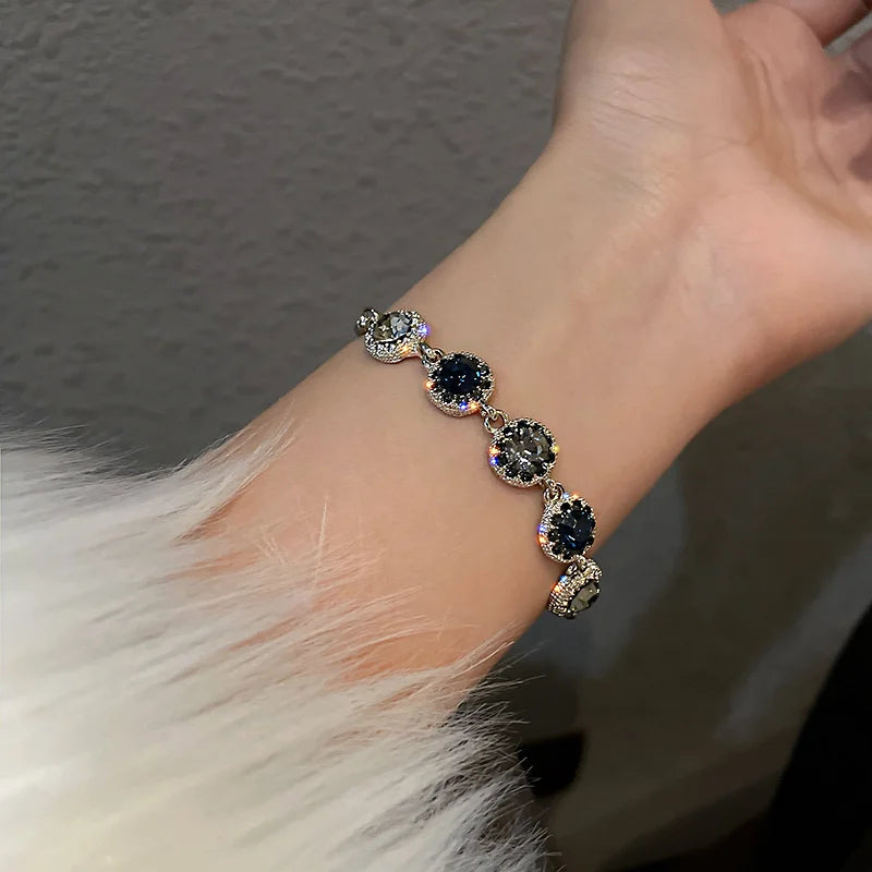 Gold-tone bracelet with linked round stones, including blue and green accents