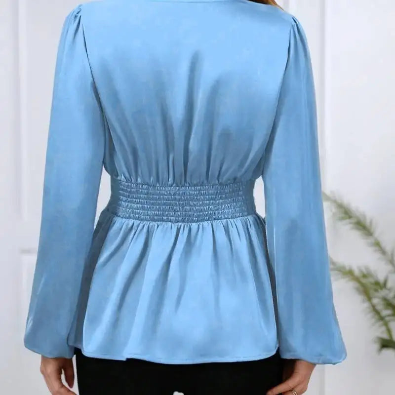 Light blue long-sleeve top with smocked waist on a white background