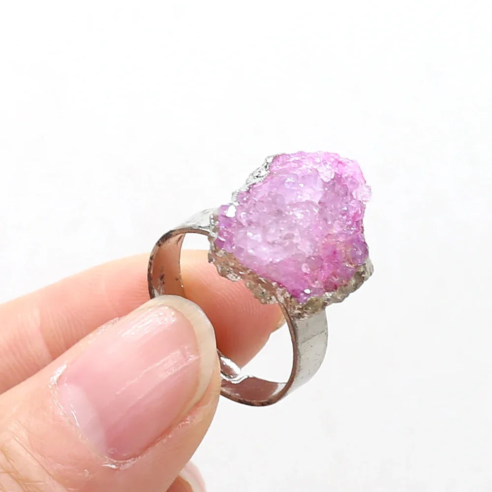 Pink crystal ring held by a hand on a white background