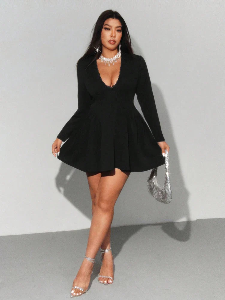 Woman wearing a black dress with long sleeves against a gray background