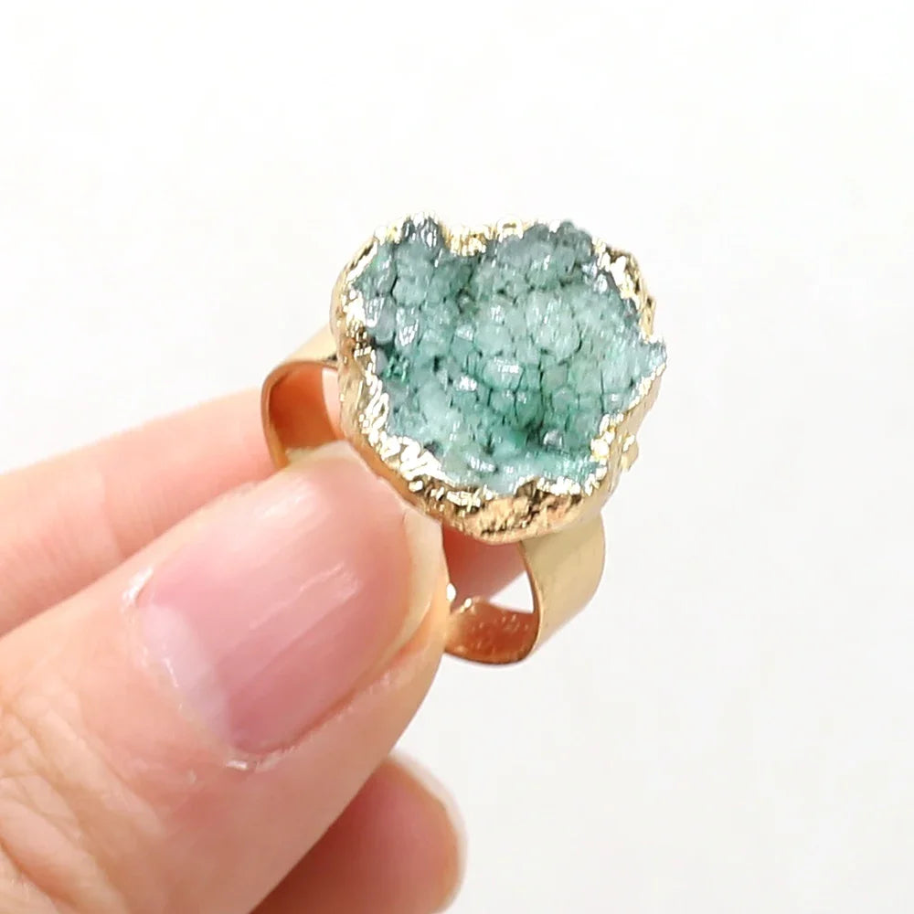 Ring with green gemstone and gold edge held by a hand on a white background