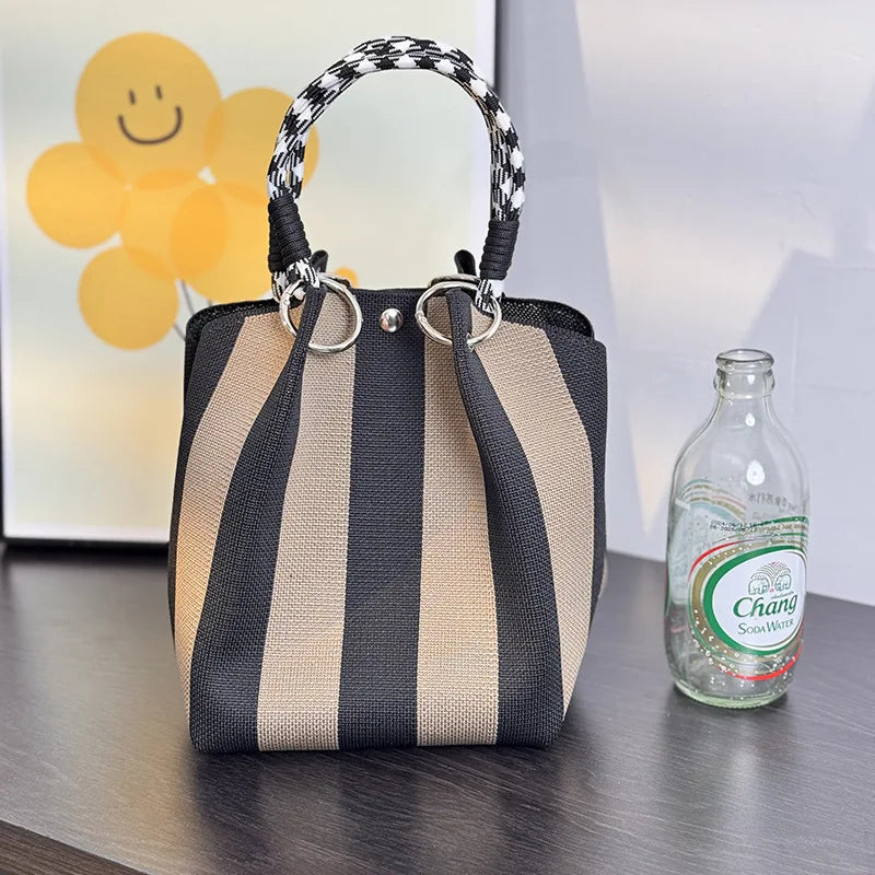 Black and tan vertical striped satchel bag with black-and-white braided top handles.