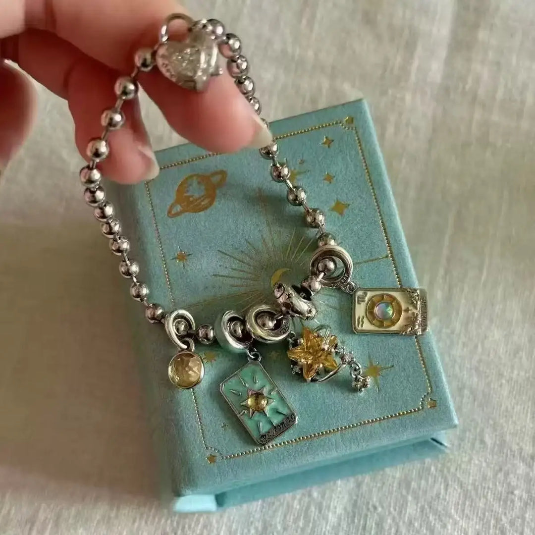 Silver charm bracelet held over a blue jewelry box with star patterns.
