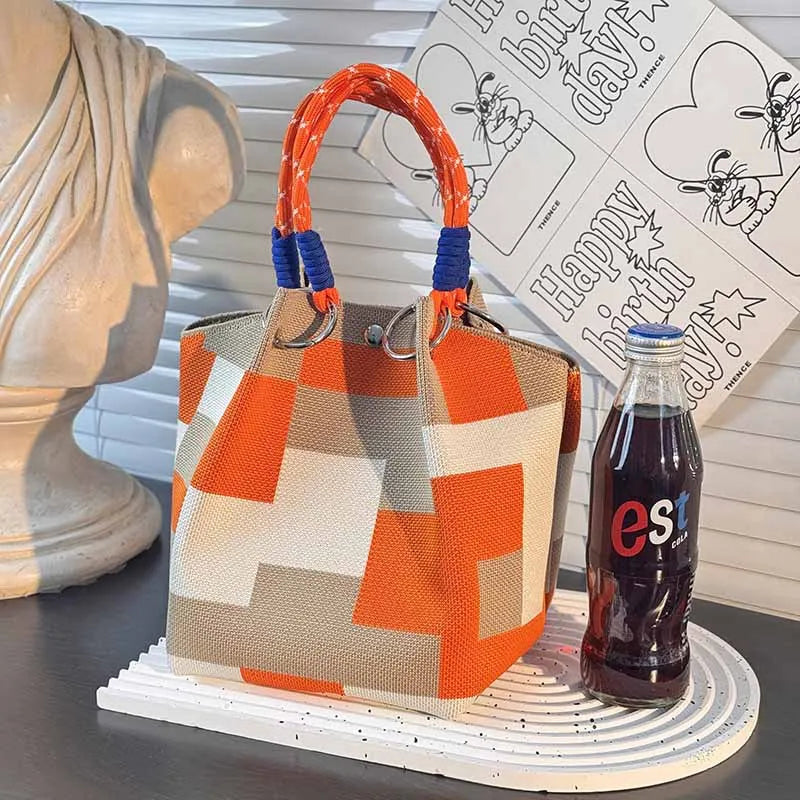 Orange, tan, and cream checkered top-handle satchel with blue rope handles and metal rings
