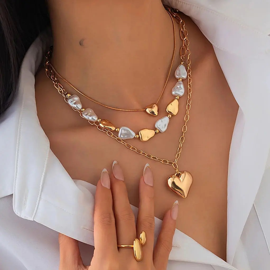 Gold necklaces with heart pendants and a matching ring on a white background