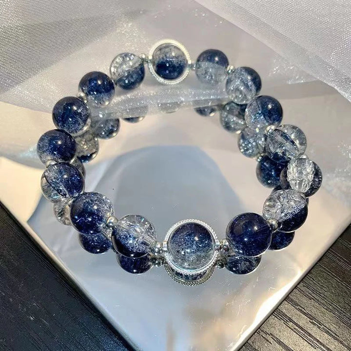 Blue and clear bead charm bracelet with round silver centerpiece and dangling charms