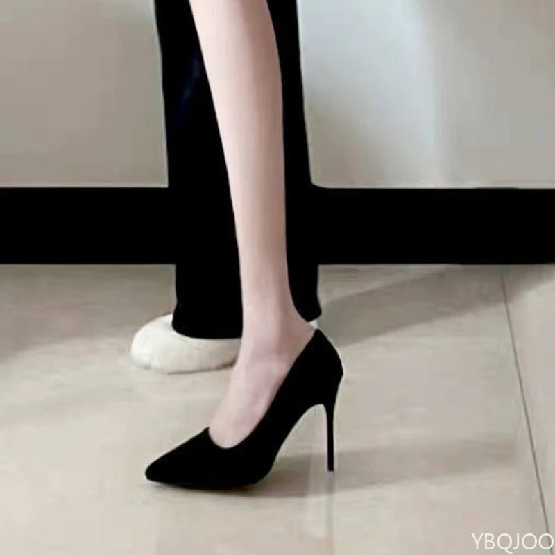 Black high-heeled shoes worn with white socks on a neutral background