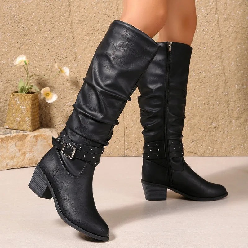Black knee-high boots with decorative elements on a neutral background