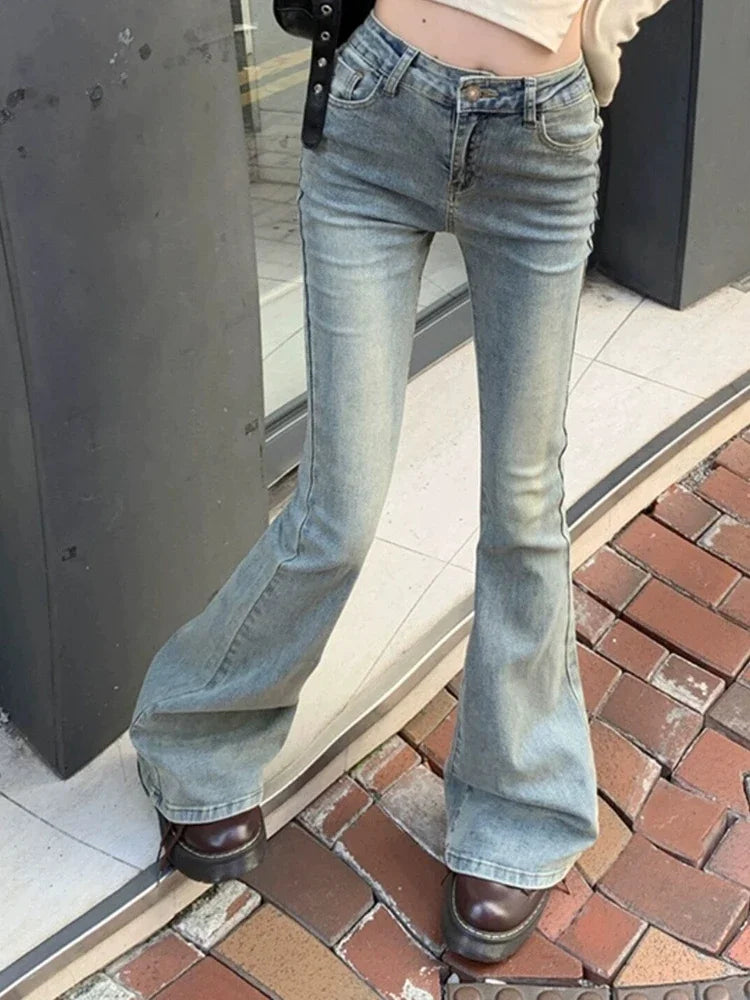 Person wearing blue flared jeans standing on a brick pavement.