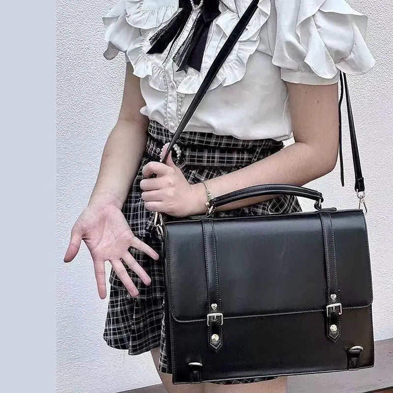 Black crossbody bag with flap front, lock details, and wide shoulder strap