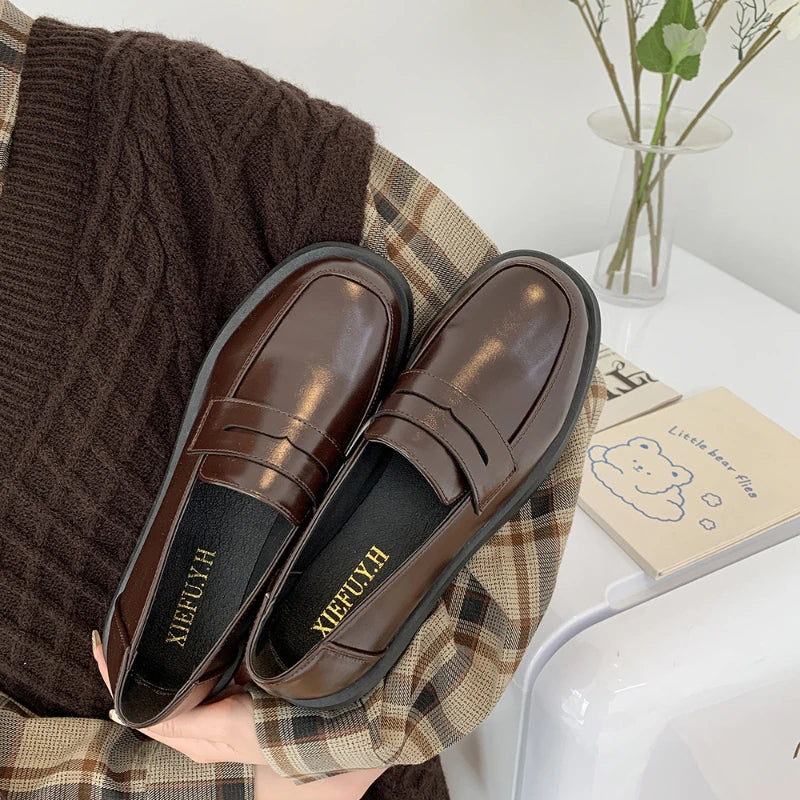 Brown loafers on a plaid fabric with a blurred background