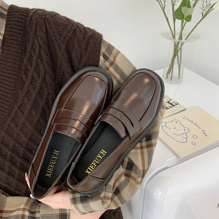 Brown loafers on a plaid fabric with a blurred background