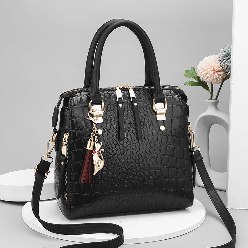 Black crocodile-embossed leather tote bag with top handles and shoulder strap