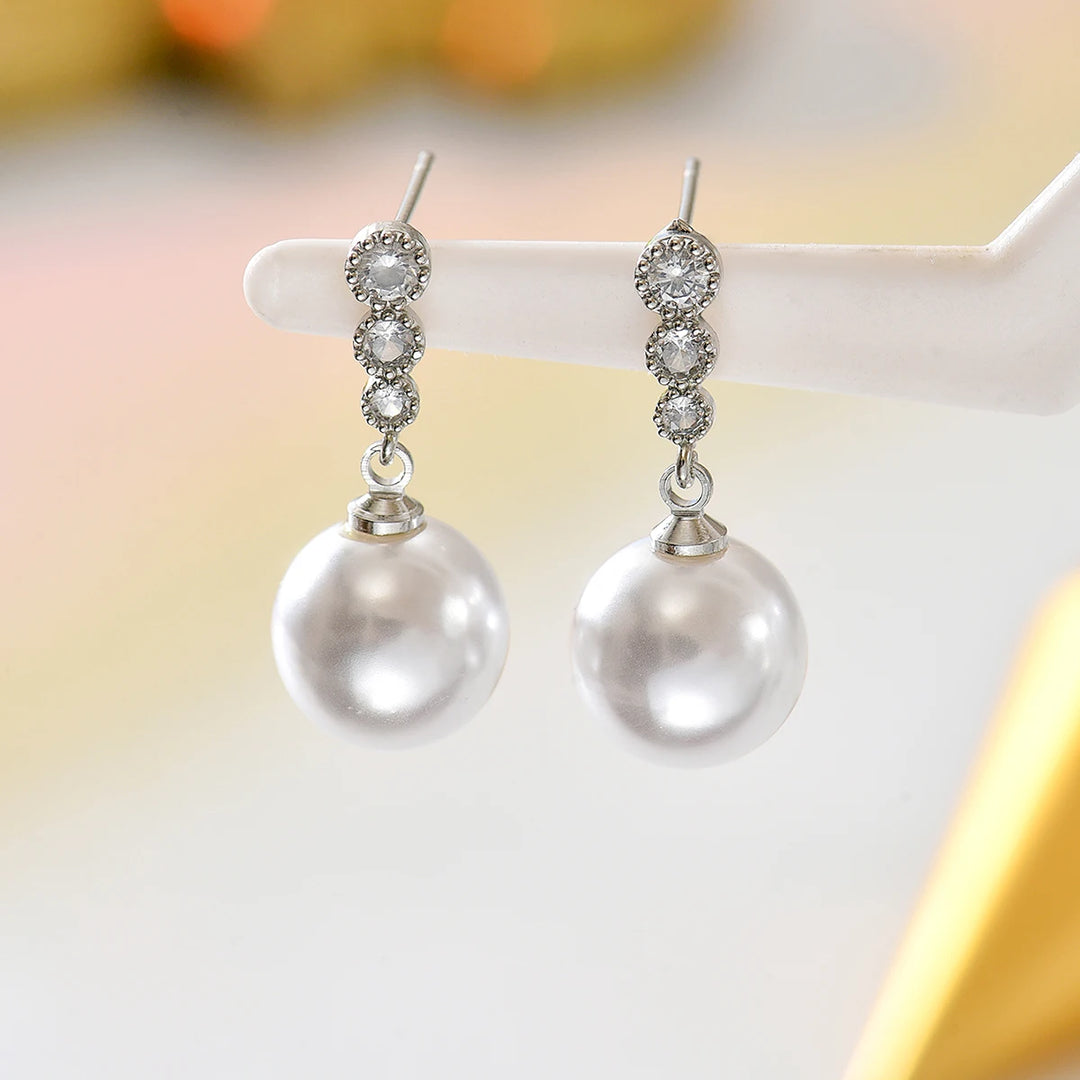 Silver-tone zircon bar with white pearl drop dangle earrings on display