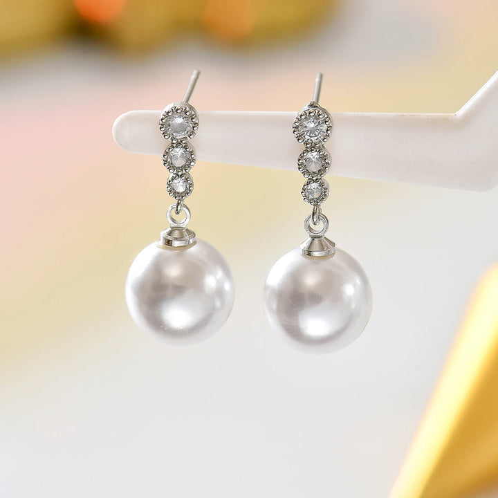 Silver-tone zircon bar with white pearl drop dangle earrings on display