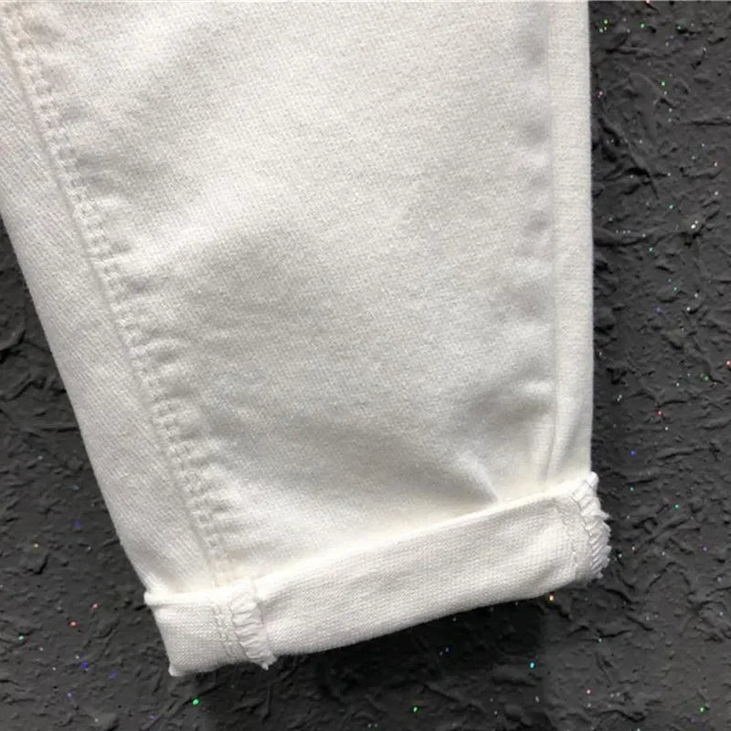 Light cream jeans cuff detail, with slightly rolled hem and stitched denim texture