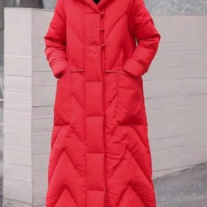 Person wearing a long red puffer coat against a neutral background
